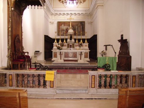 Il presbiterio sistemato durante gli anni Settanta: altare ricavato dal taglio della mensa tridentina (1975); ambone ligneo (a destra) e cattedra episcopale (a sinistra) inserita nel baldacchino preesistente